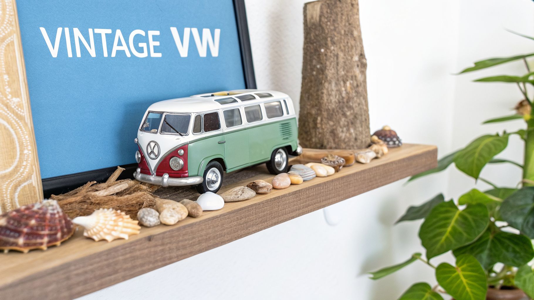 A coastal-themed shelf with a vintage VW van toy, framed art, seashells, and pebbles.