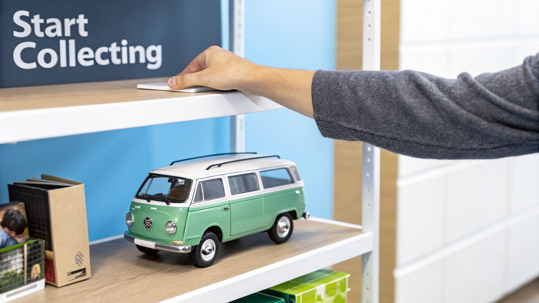 A hand reaches over a wooden shelf with a green and white toy VW van and a "Start Collecting" sign.