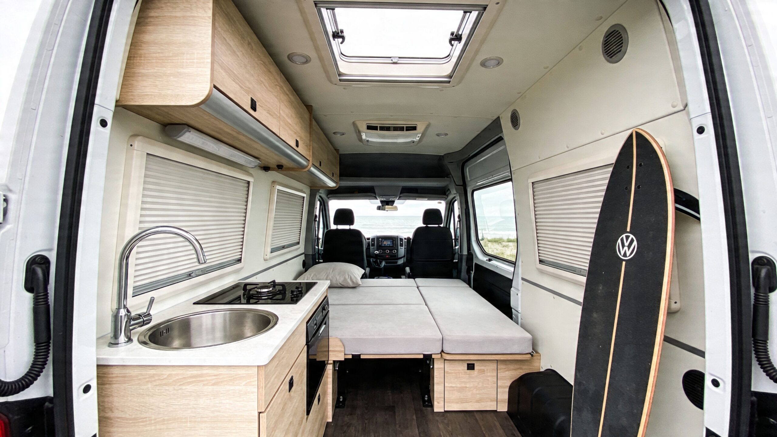 Interior view of a modern Volkswagen Crafter camper van featuring a compact kitchenette and sleeping area.