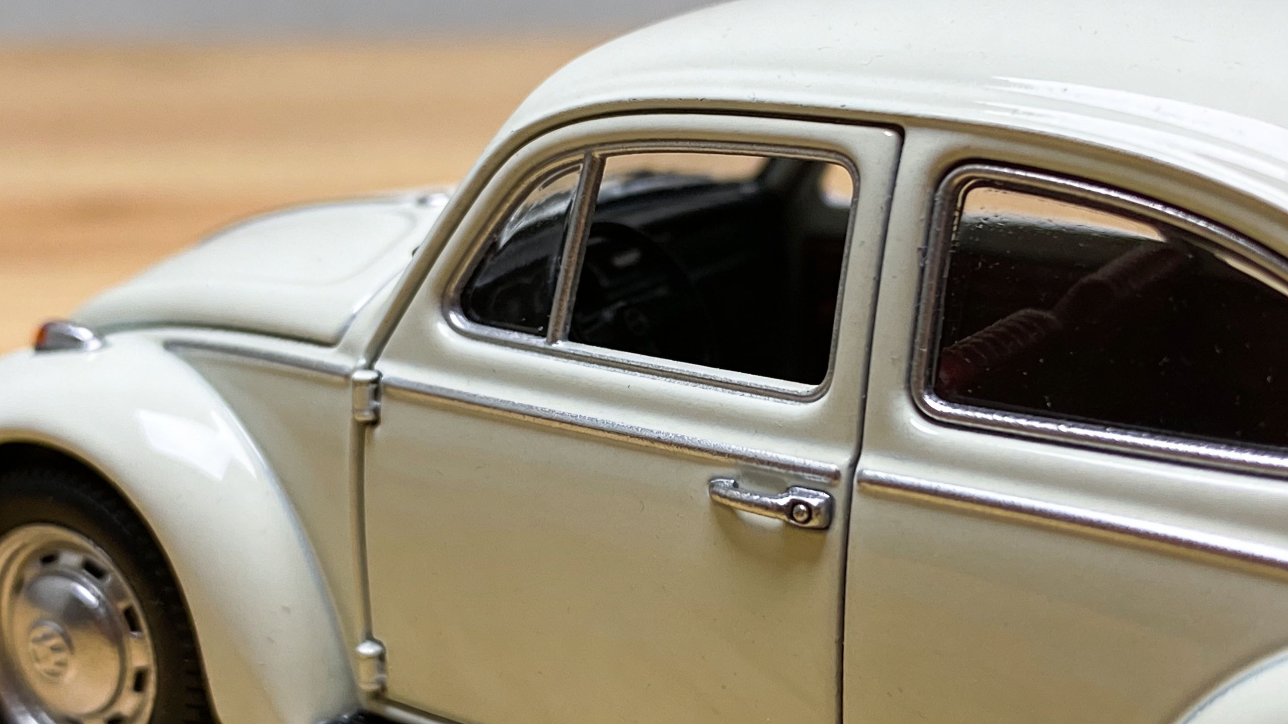 A close-up side view of a white Volkswagen Beetle miniature toy car model.