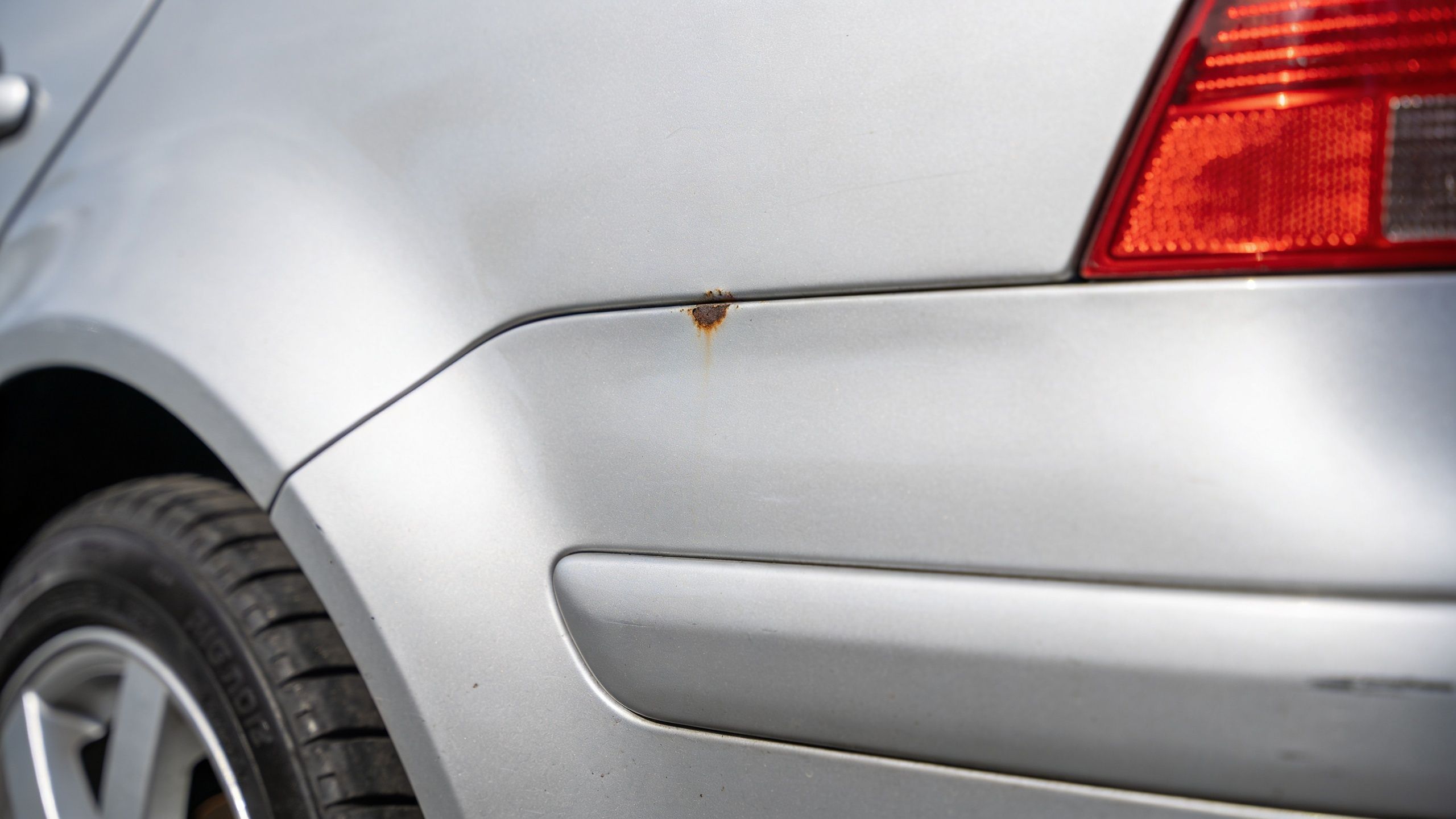 A close-up shot of a silver Volkswagen car body showing a small patch of rust near the seam.
