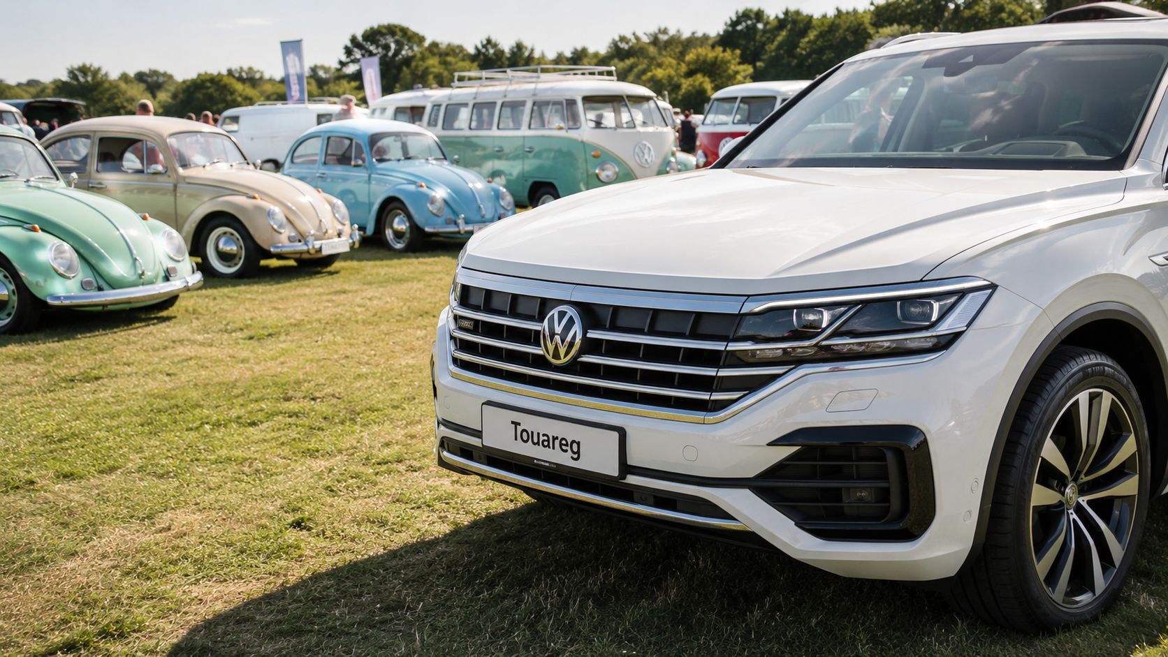 A sleek white Volkswagen Touareg parked on grass at an outdoor car exhibition with classic Beetles nearby.