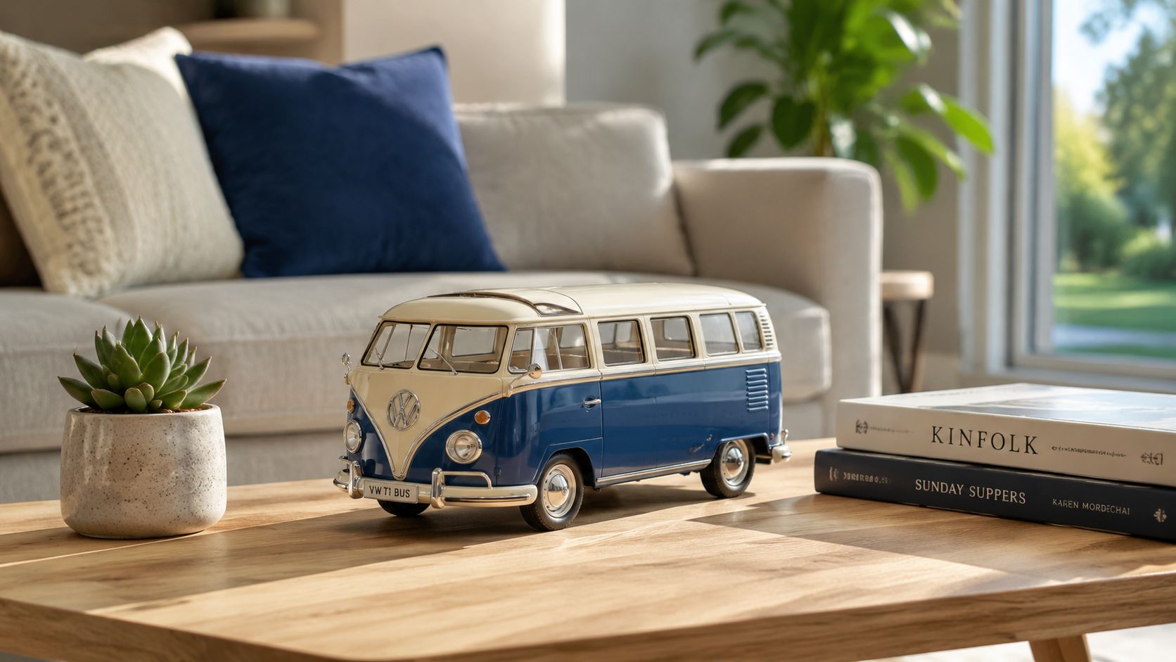 A classic blue and cream toy Volkswagen T1 bus model sits on a wooden coffee table near books.