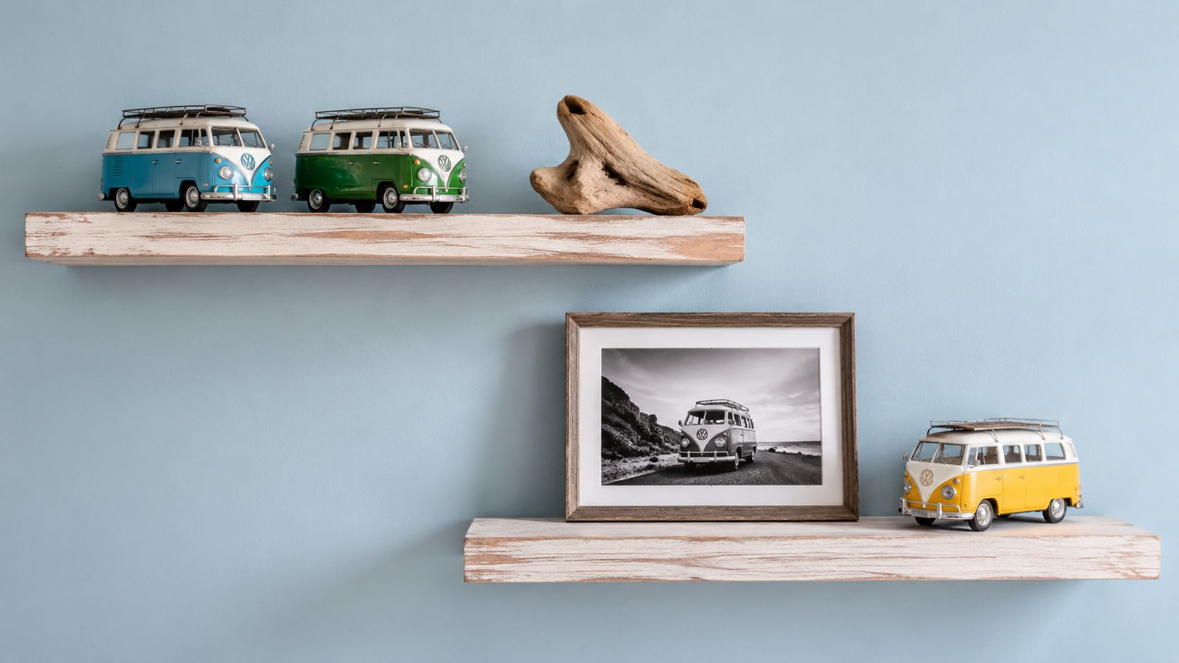 Two rustic wooden shelves on a light blue wall holding vintage Volkswagen bus toy models and decor.