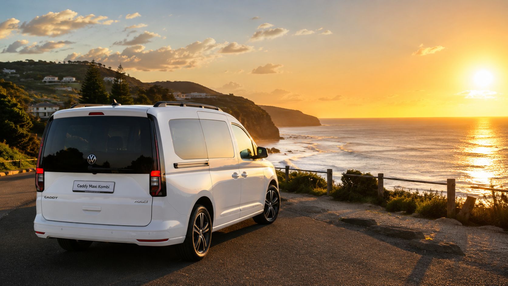 A white Volkswagen Caddy Maxi Kombi parked on a scenic coastal road during a beautiful golden sunset.
