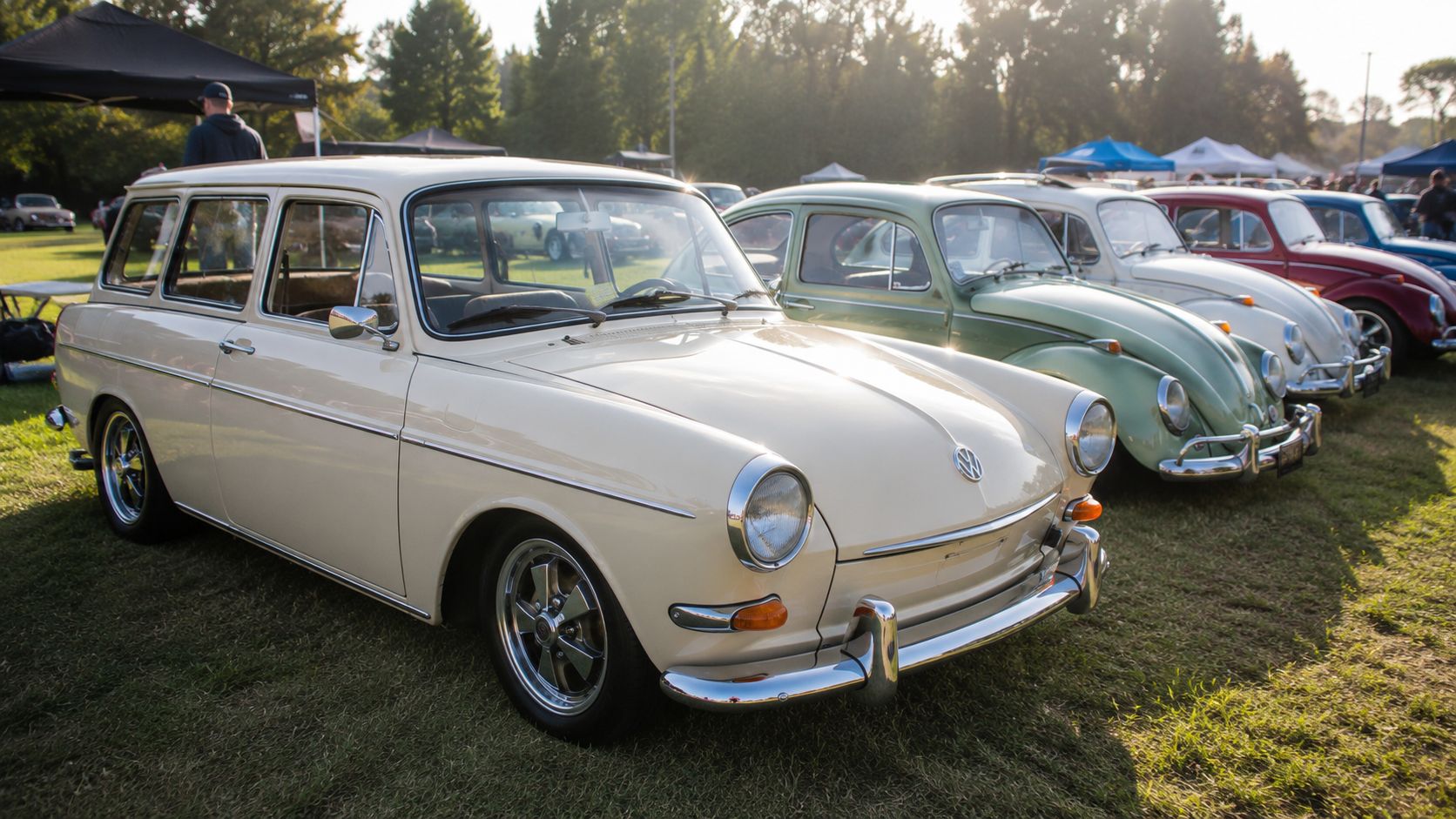 A beige Volkswagen Type 3 Squareback parked on a grassy field at an outdoor vintage car show.