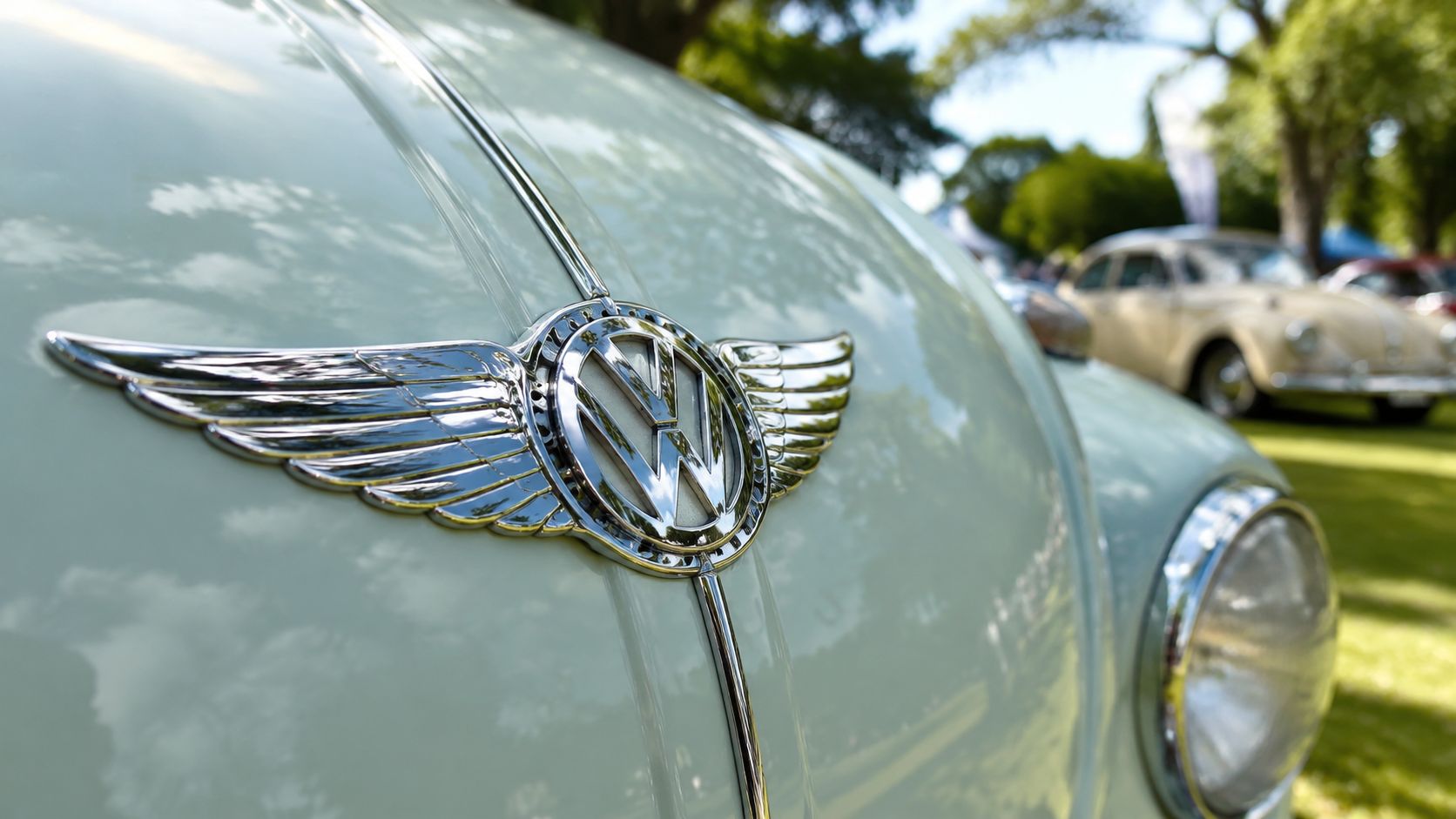 A close-up view of a chrome Volkswagen car emblem featuring decorative wings on a white vehicle.