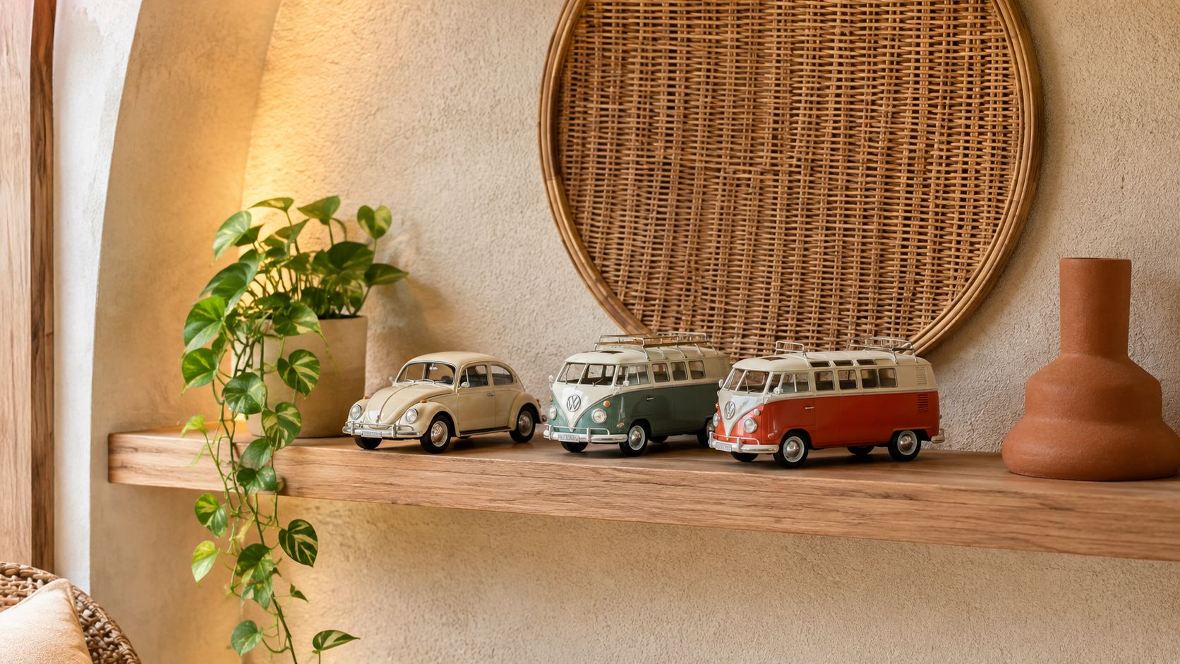 A rustic wooden shelf displays three vintage Volkswagen toy cars beside a potted plant and terracotta vase.