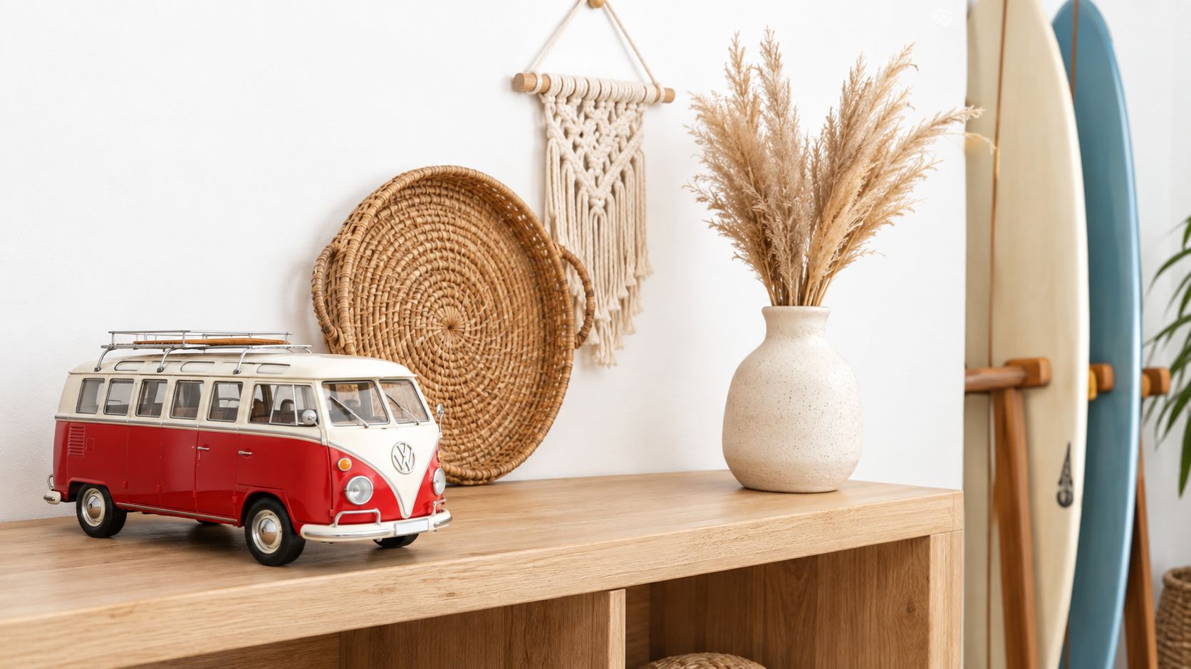 A miniature red and white Volkswagen van model on a wooden shelf next to decorative boho style accessories.