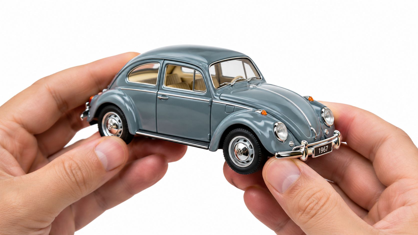 A pair of hands carefully holding a small grey vintage Volkswagen Beetle diecast model car.