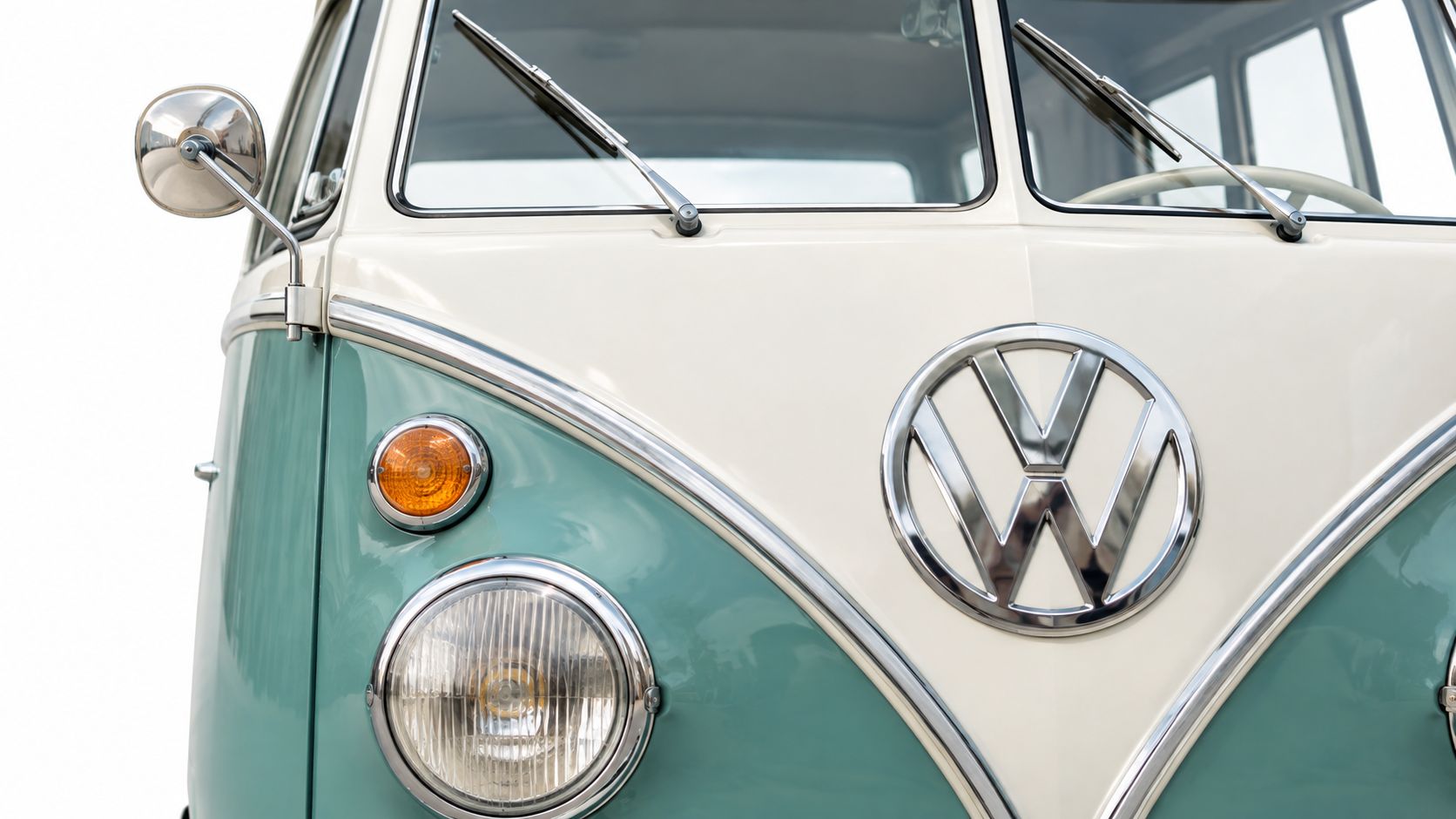 Close-up front view of a vintage Volkswagen Kombi bus featuring signature white and teal paint colors.