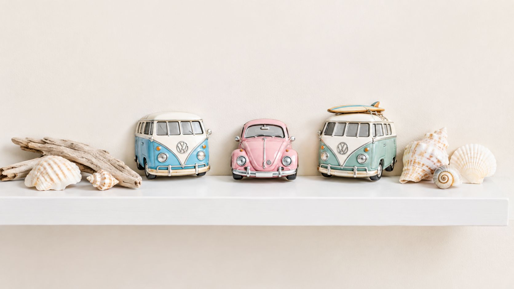 A minimalist shelf displaying miniature Volkswagen cars, driftwood pieces, and various seashells on a plain wall.