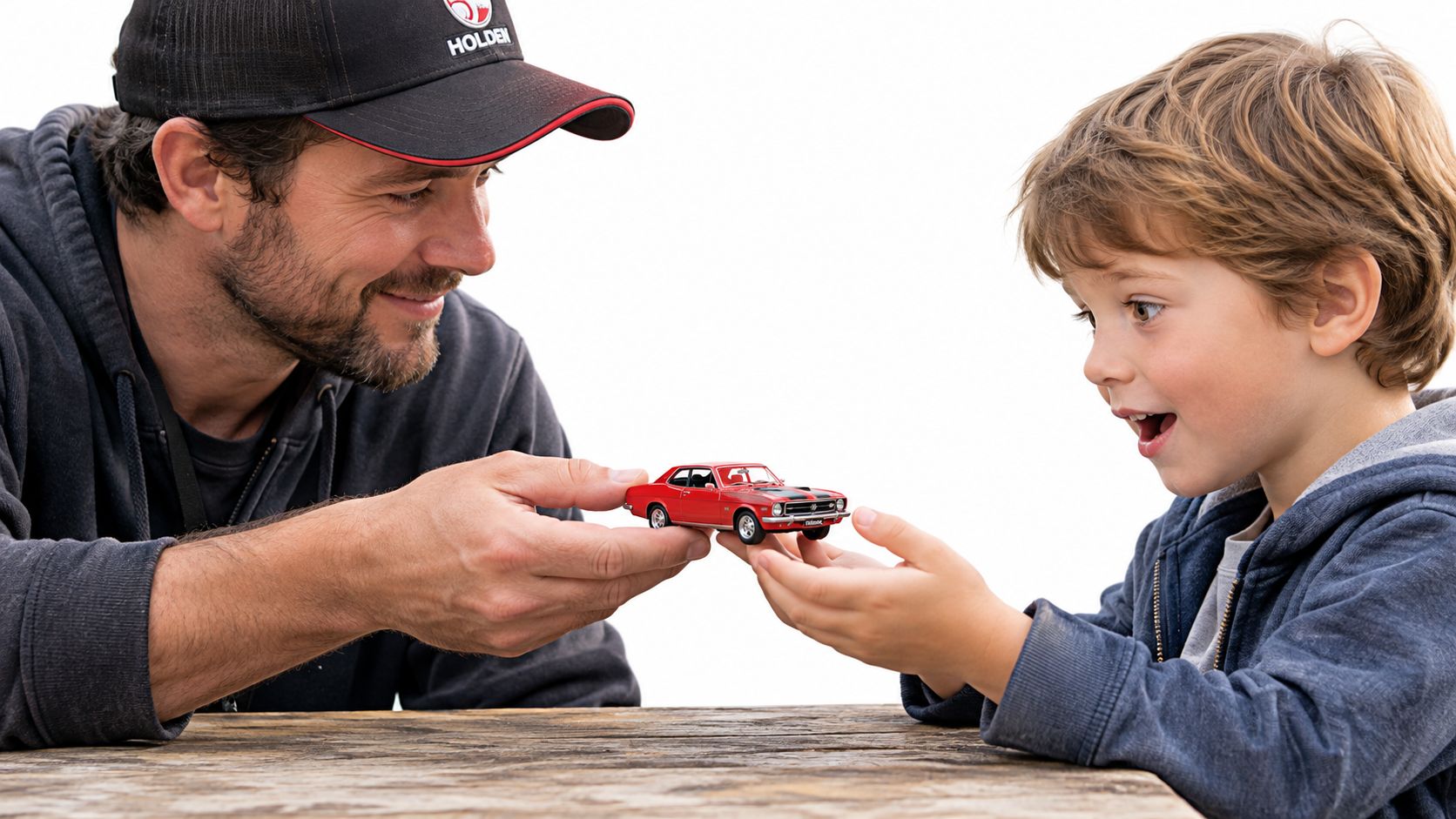 A father showing a red classic collectible model car to his excited young son.